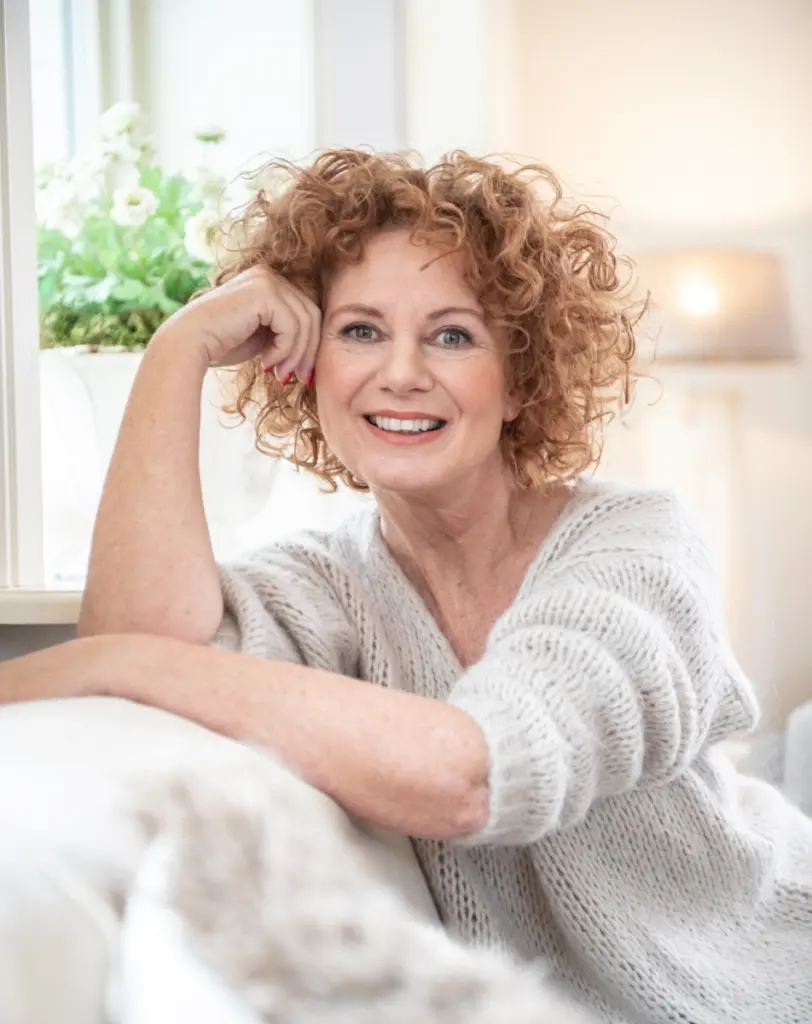Frau mit lockigem Haar lacht in Kamera als Symbolbild für das Life Coaching
