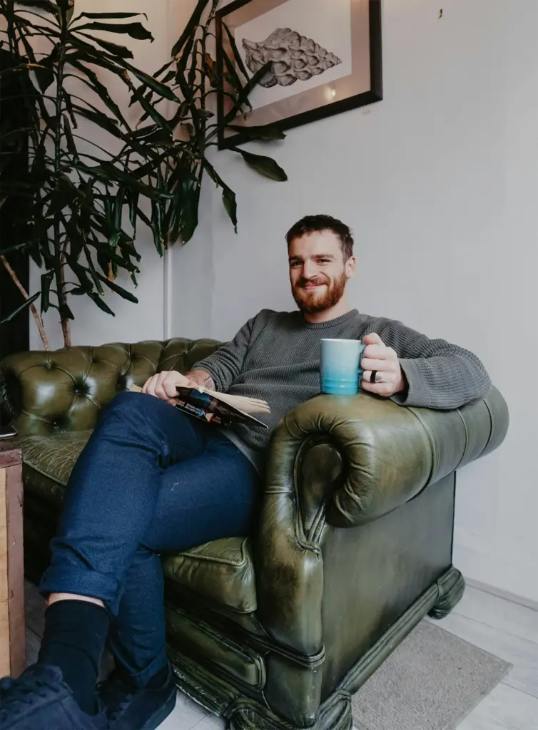 Mann sitzt lächelnd in einem Sessel und lächelt den Betrachter an als Symbolbild für das Life Coaching