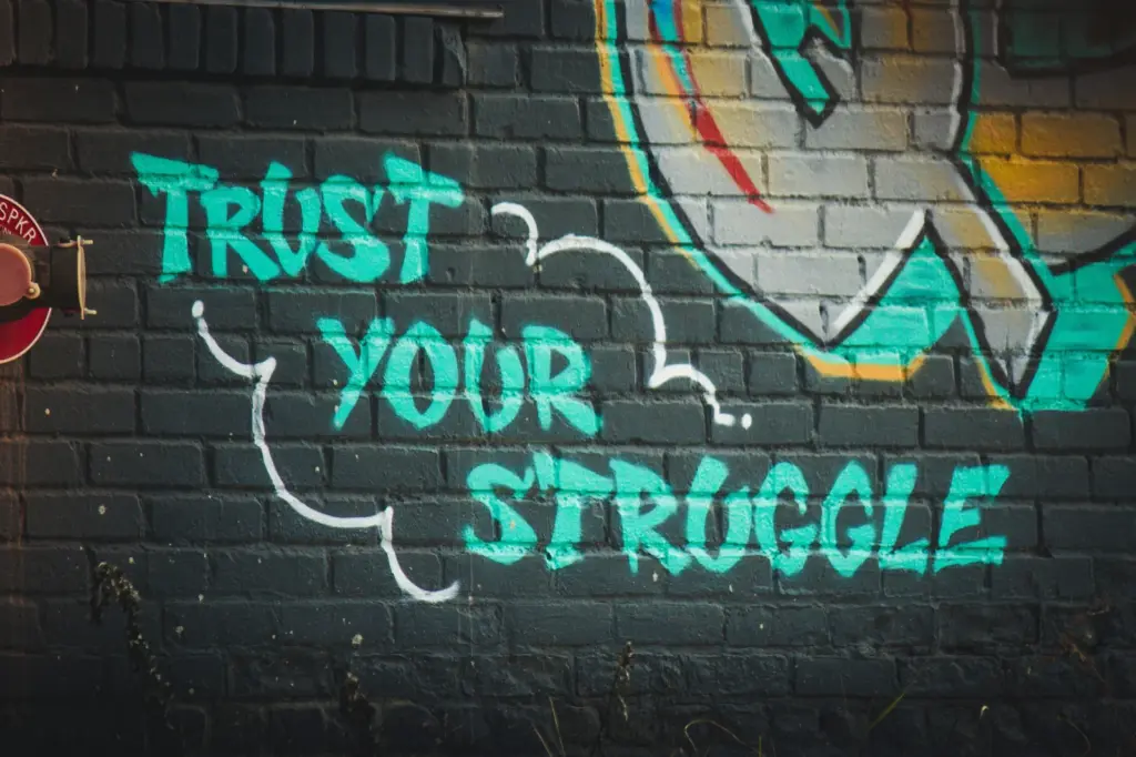 Mauerwand mit dem Spruch "Trust your Struggle" als Symbolbild für das Life Coaching